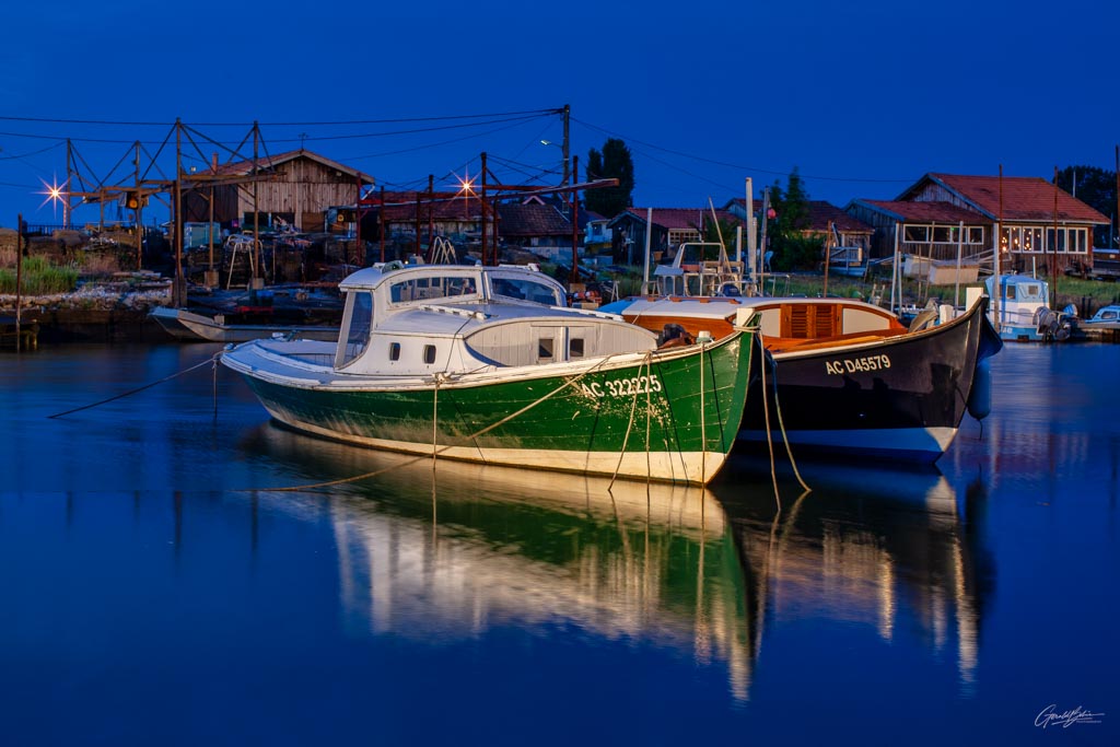 Deux pinasses colorées amarrées au port de La Teste-de-Buch, reflétant l'authenticité et le charme du bassin d'Arcachon, a la tombée de la nuit