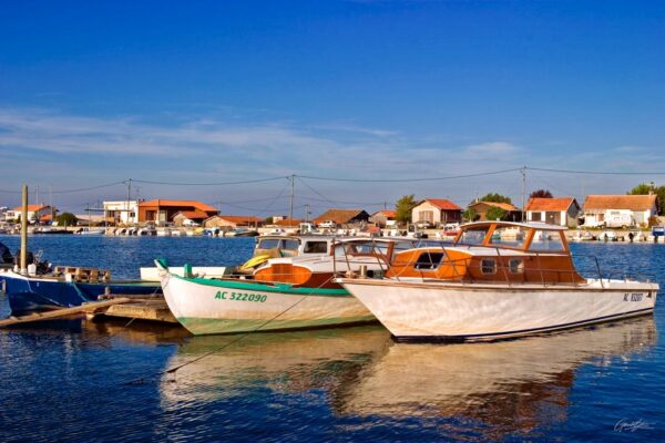 Deux pinasses colorées amarrées au port de La Teste-de-Buch, reflétant l'authenticité et le charme du bassin d'Arcachon, entourées de paysages marins